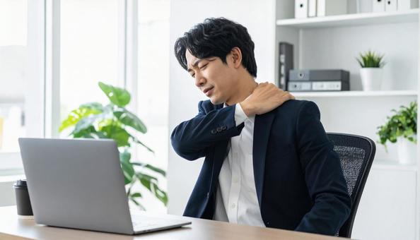 デスクワークで肩こりに悩むビジネスマン デスクワークで肩こりに悩むビジネスマンの写真
