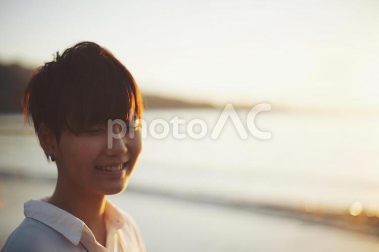夕日の砂浜にいるショートカットの女の子 女性,笑顔,お出かけの写真素材