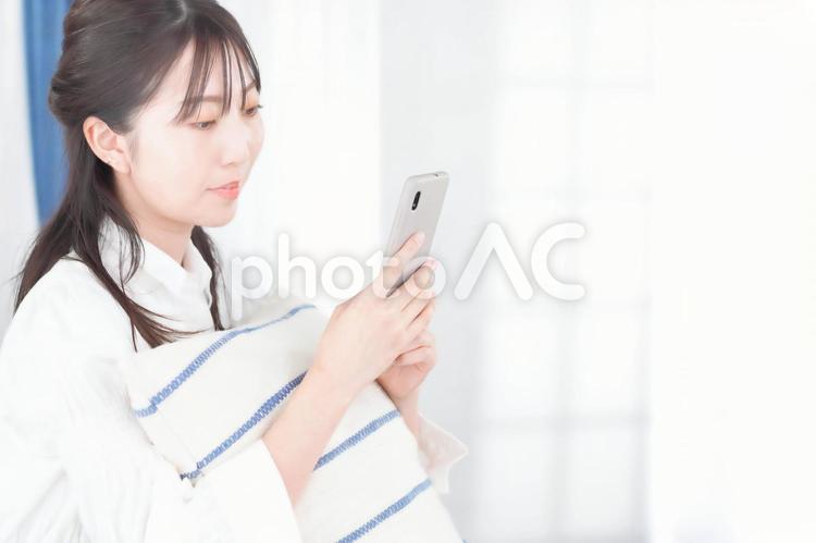 クッションを抱えながらスマホを使う女性 女性,日本人,大人の写真素材