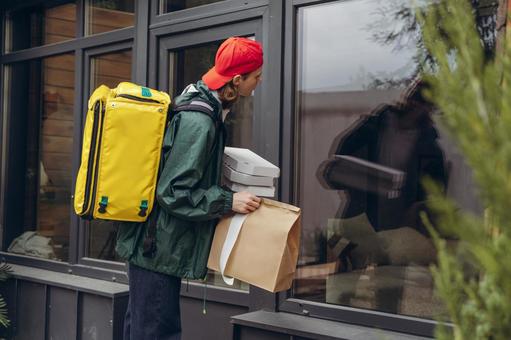 ガラス窓から配達先の家を覗き込むフードデリバリーの男性 配達,デリバリー,配送の写真素材