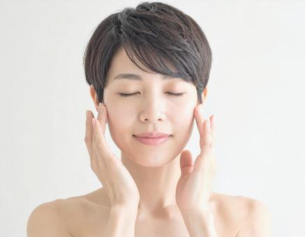 フェイスマッサージをする女性 フェイスマッサージをする女性の写真