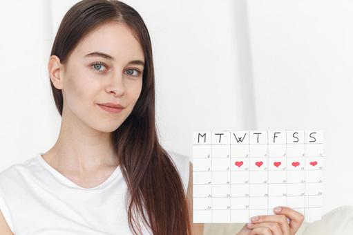 月経期間を示すカレンダーを手に持ったカメラ目線の女性 生理,月経,女性の写真素材