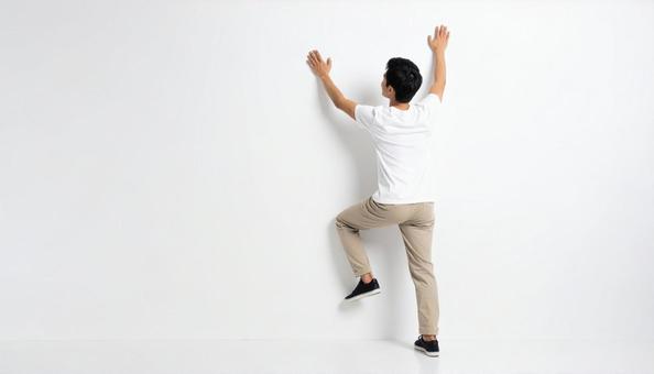 白い壁にのぼって乗り越える日本人男性 白い壁にのぼって乗り越える日本人男性の写真