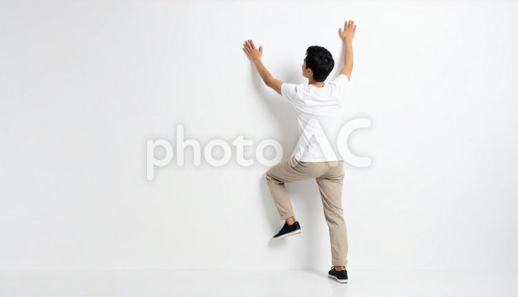 白い壁にのぼって乗り越える日本人男性 壁,乗り越え,男性の写真素材