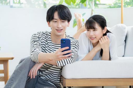 リビングでスマホを見る若いカップル リビングでスマホを見る若いカップル 夫婦,カップル,リビングの写真素材
