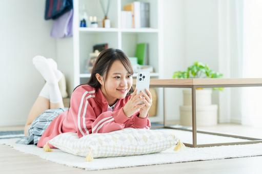 部屋でスマホを見る女子高生 部屋でスマホを見る女子高生 スマートフォン,女子高生,高校生の写真素材