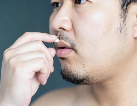 薬を飲む肥満男性 薬を飲む肥満男性の写真