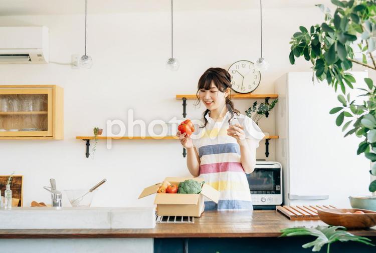 入った野菜と女性（スマホ・笑顔） キッチン,野菜宅配,スマホの写真素材