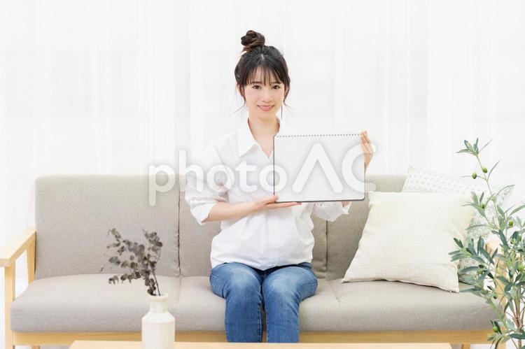 ソファに座って小さいスケッチブックを持つ若い女性 女性,ソファ,家の写真素材