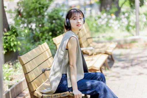 新緑の中ヘッドフォンで音楽を聴く若い女性 新緑の中ヘッドフォンで音楽を聴く若い女性 女性,人物,ヘッドフォンの写真素材