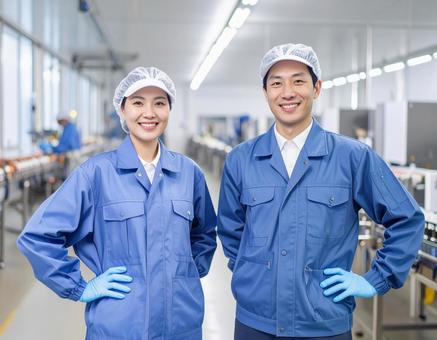 食品工場で制服姿で笑顔の男女の作業員の写真