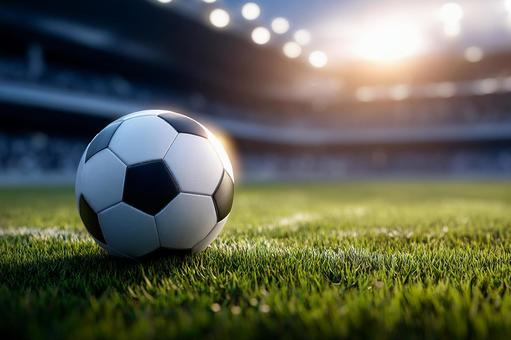 スタジアムの芝生に置かれたサッカーボール スタジアムの芝生に置かれたサッカーボールの写真