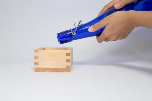 青い瓶から木製の枡に注ぐ手元 枡,コピースペース,日本酒の写真素材