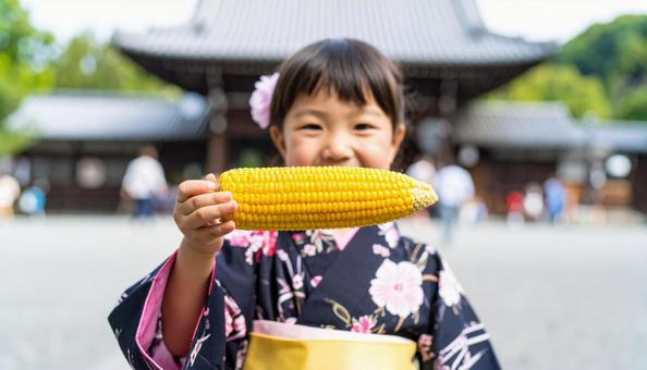 焼きとおもろこしを手に持つ浴衣姿の子ども 焼きとおもろこしを手に持つ浴衣姿の子どもの写真