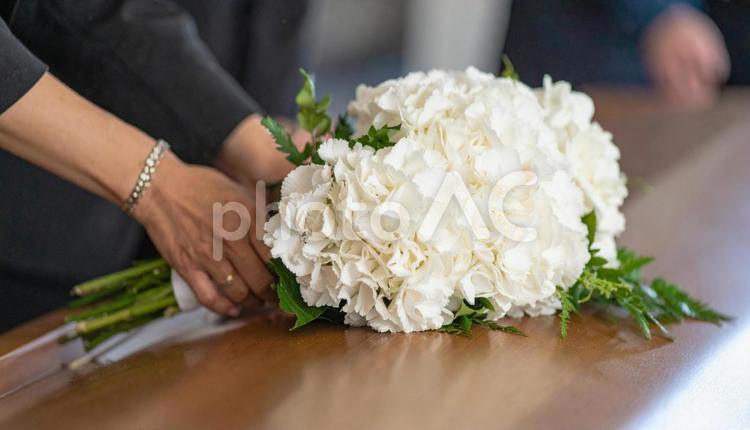 葬式でお棺に白い花束を入れる人の手もと 白い花,喪,お棺の写真素材