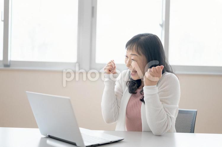 PCとガッツポーズの中高年女性(その４４ 女性,ビジネスウーマン,オペレーターの写真素材