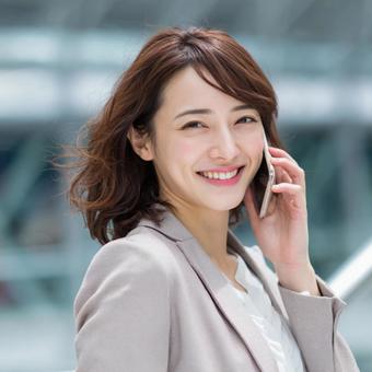 スマホで通話するスーツの女性 スマホで通話するスーツの女性の写真