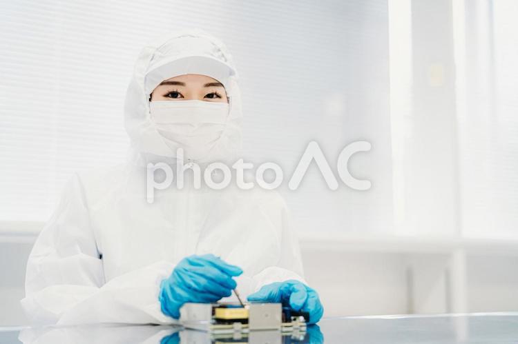 クリーンルームで精密機器を扱う女性 クリーンルームで精密機器を扱う女性 工場,製造業,精密機器の写真素材