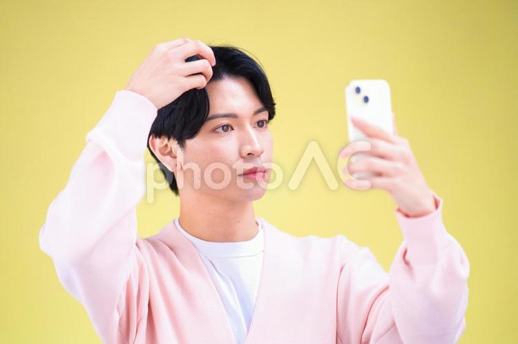 スマホを持ち髪を触る男性 男性,スマートフォン,持つの写真素材