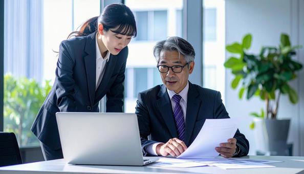 データを見ながら相談する上司と部下 データを見ながら相談する上司と部下の写真
