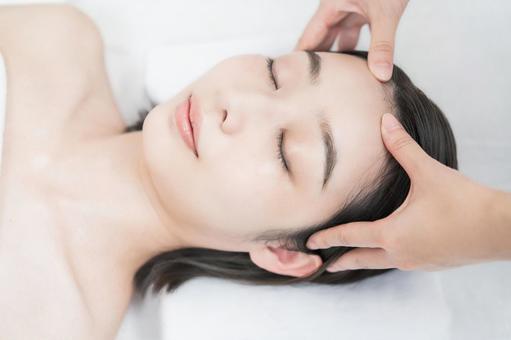 A young woman whose head is massaged at an esthetic salon A young woman whose head is massaged at an esthetic salon