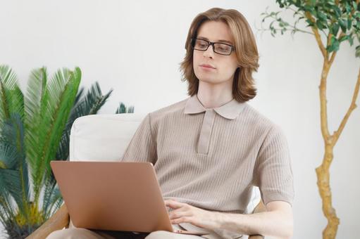座って膝の上でノートパソコンを使う若い男性 男性,外国人,欧米人の写真素材