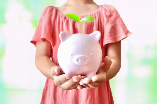 子供と豚の貯金箱に葉っぱの芽生え 子供と豚の貯金箱に葉っぱの芽生えの写真