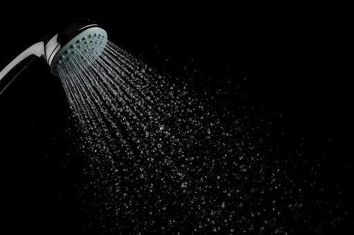 黒背景で広がるシャワーの飛沫の写真