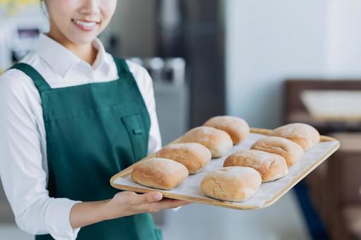 パンをすすめる若い女性の店員 ベーカリー,パン,パン屋の写真素材