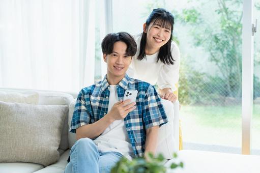 リビングでスマホを見るカップル リビングでスマホを見るカップル スマホ,笑顔,カップルの写真素材