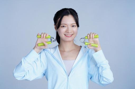 水色の服の女性が健康器具を両手に持つ 女性,ハンドグリップ,握るの写真素材