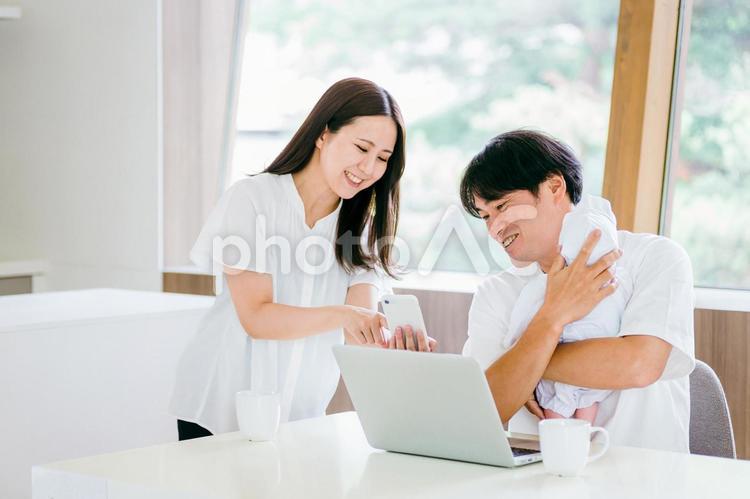 スマホを使う女性と赤ちゃんを抱く男性 赤ちゃん,育児,子育ての写真素材