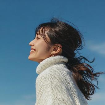 風になびく髪と、明るい笑顔が印象的な女性 風になびく髪と、明るい笑顔が印象的な女性の写真