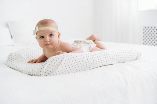 うつ伏せでポーズする頭にリボンを付けた赤ちゃん うつ伏せでポーズする頭にリボンを付けた赤ちゃん 赤ちゃん,腹ばい,うつ伏せの写真素材