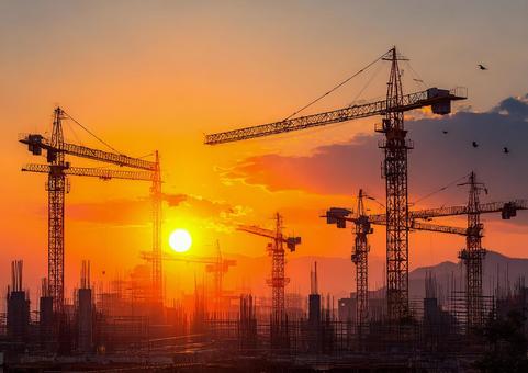 夕焼けに染まる建設現場のクレーン 夕焼けに染まる建設現場のクレーンの写真