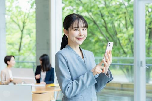 スマホを操作するビジネスウーマン スマホを操作するビジネスウーマン スマホ,笑顔,ビジネスウーマンの写真素材