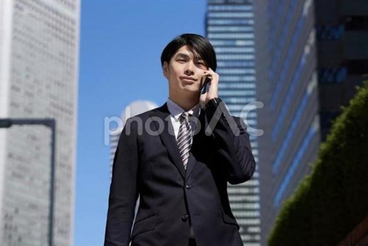 オフィス街で電話をするビジネスマン ビジネスマン,男性,スマホの写真素材