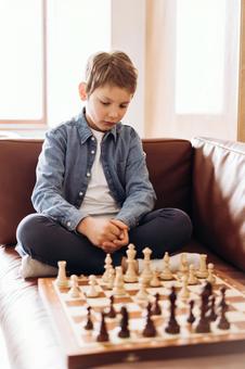 ソファにあぐらをかいてチェスをする男の子 ソファにあぐらをかいてチェスをする男の子の写真
