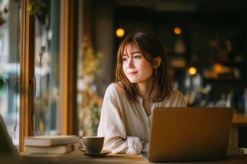 カフェでリモートワークする女性の写真