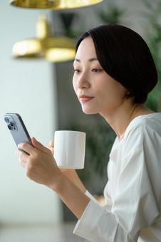 カフェでスマホを操作する日本人女性 カフェでスマホを操作する日本人女性の写真
