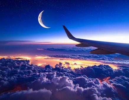 飛行機の窓から見える雲海と月の写真