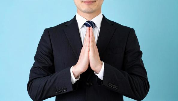 両手をあわせてお願いしているビジネスマン 両手をあわせてお願いしているビジネスマンの写真