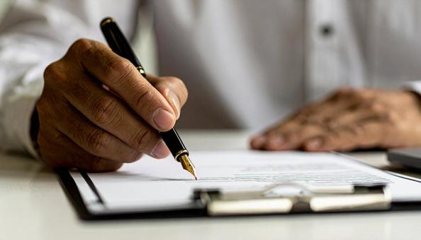 契約書に万年筆でサインをする男性の手 契約書に万年筆でサインをする男性の手の写真