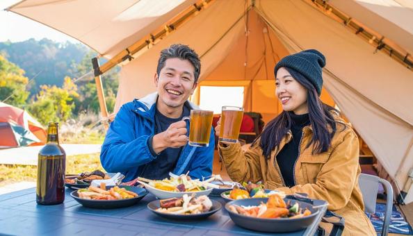 秋のキャンプ場でビールを飲む日本人男女 秋のキャンプ場でビールを飲む日本人男女の写真
