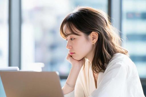 PCを前に悩むビジネス女性 PCを前に悩むビジネス女性の写真