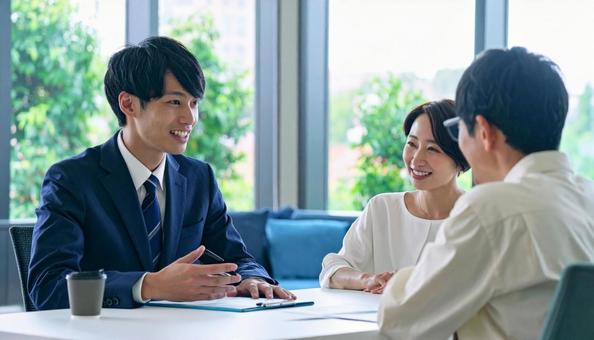 男性営業マンの説明を聞く夫婦 男性営業マンの説明を聞く夫婦の写真