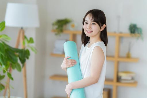 リビングでヨガをする若い女性 リビングでヨガをする若い女性 トレーニング,ヨガマット,持つの写真素材