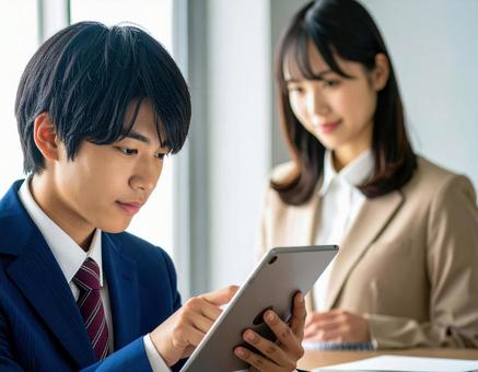 タブレットを使い勉強する男子学生 タブレットを使い勉強する男子学生の写真