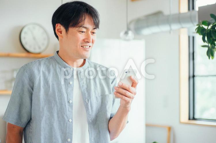 家でスマホを使う男性（アプリ） スマホ,男性,スマートフォンの写真素材