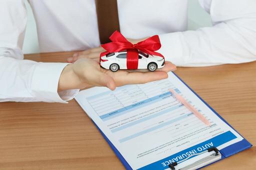 リボンを巻いた車の模型を持つ手元 保険業,事務職,接客業の写真素材